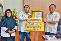 Bupati Touna, Ilham Lawidu Saat Menyerahkan Piagam Penghargaan dan Bonus Kepada Lurah Labiabae Sebagai Bentuk Apresiasi