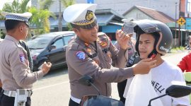 Kasatlantas Polres Touna, Siswanto Saat Memakaikan Helm Gratis Kepada Pengendara Yang Melintas di Jalan Mohamad Hatta Kecamatan Ampana Kota