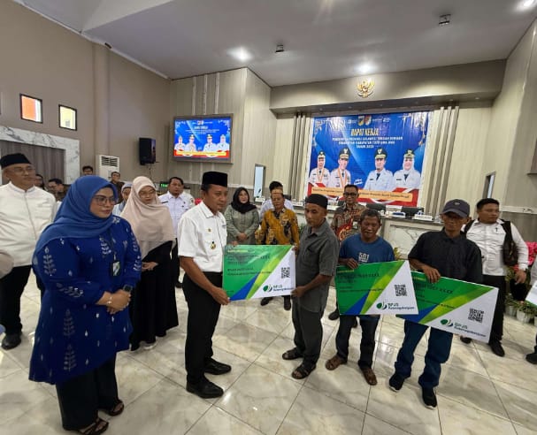 Bupati Touna Ilham Lawidu Saat Menyerahkan Kartu Peserta BPJS Ketenagakerjaan di Kegiatan Rapat Kerja Bersama Gubernur Sulteng.
