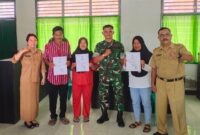 Sekretaris Disdukcapil Touna, Hasbullah Daeng Masikki Saat Menyerahkan Kartu Keluarga Gratis Pada Kegiatan Pelayanan Keliling.