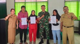 Sekretaris Disdukcapil Touna, Hasbullah Daeng Masikki Saat Menyerahkan Kartu Keluarga Gratis Pada Kegiatan Pelayanan Keliling.