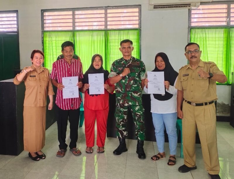 Sekretaris Disdukcapil Touna, Hasbullah Daeng Masikki Saat Menyerahkan Kartu Keluarga Gratis Pada Kegiatan Pelayanan Keliling.