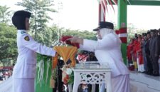 Wakil Bupati Surya Lapasiri Saat Menyerahkan Bendera Pusaka Merah Putih Kepada Anggota Paskibraka Untuk di Kibarkan Pada Upacara Peringatan Hari Kemerdekaan Republik Indonesia.